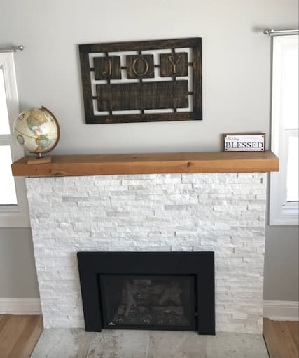 Finished gas fireplace insert with a stone surround and wood mantel