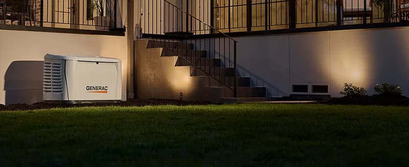 Generac home standby generator installed beside a house at night