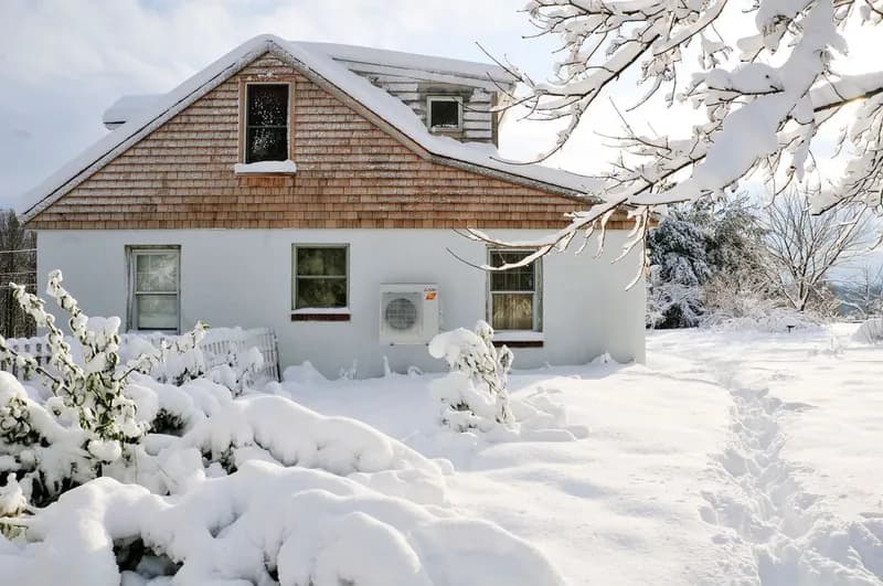 Mitsubishi Electric H2i outdoor heat pump unit running beside a snow-covered home
